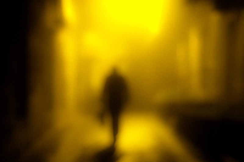 Blurred person in a yellow-lit alley