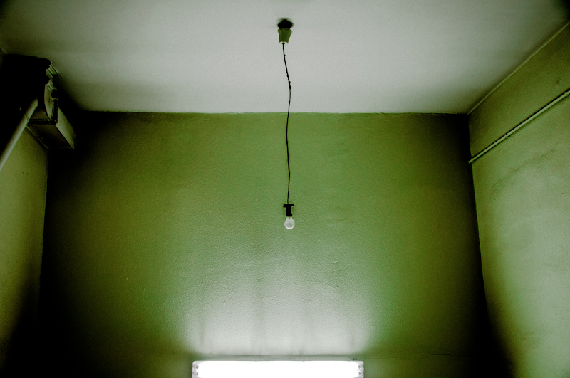 Single bulb hanging in a sparse green room