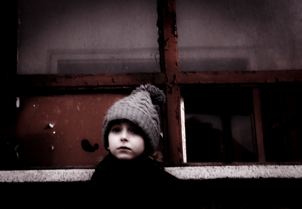 Child looking through a dark window