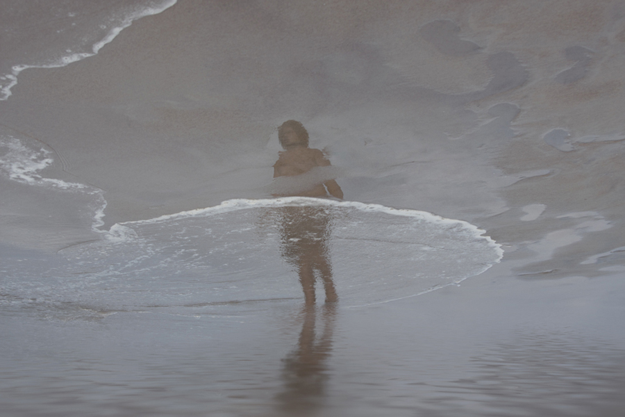 Figure standing amid waves in pale mist