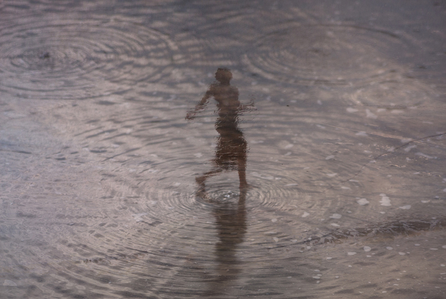 Small figure reflected on wet shoreline