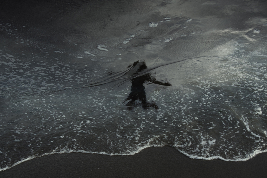 Figure walking along a wave-washed shore