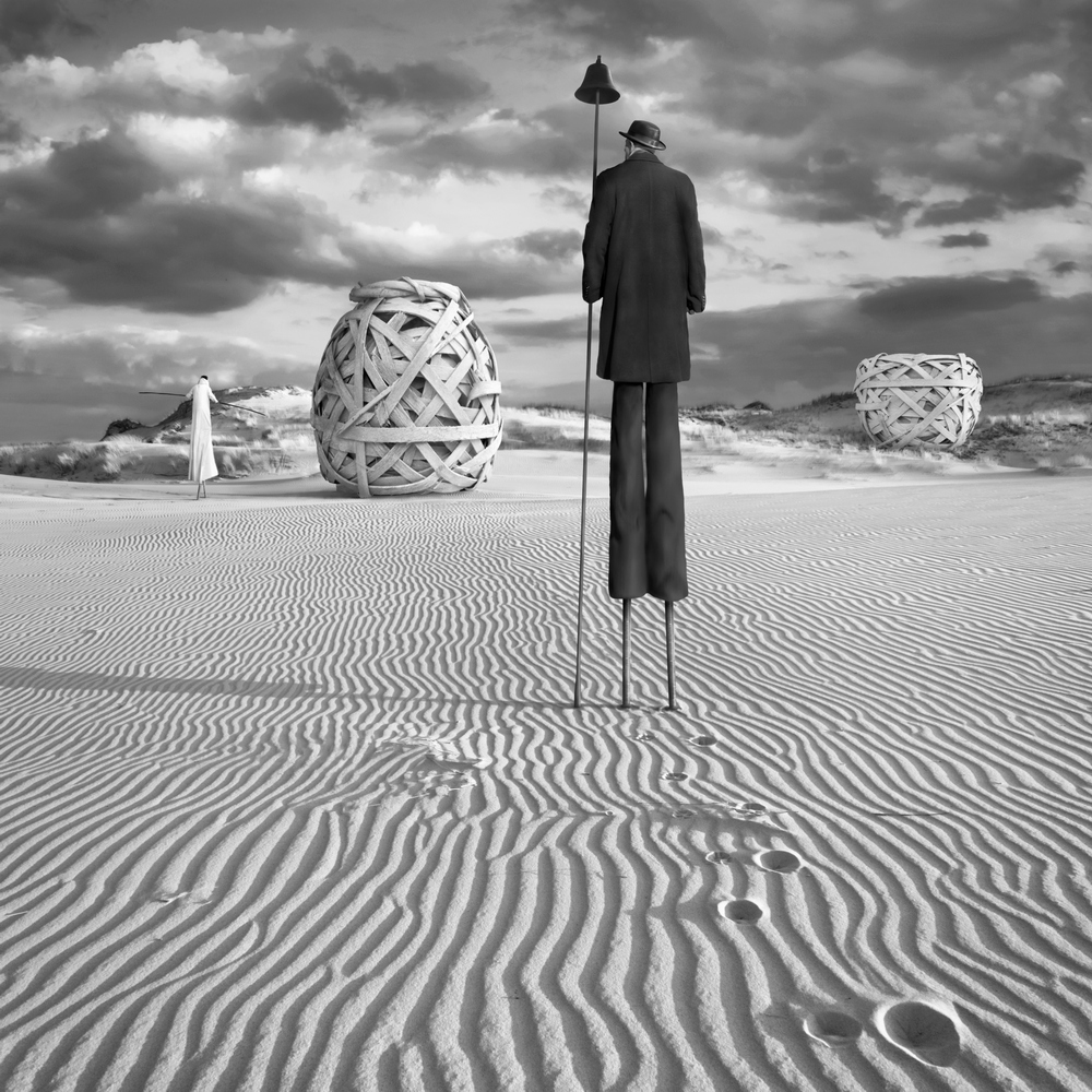 Stilt walker in a patterned sandy landscape