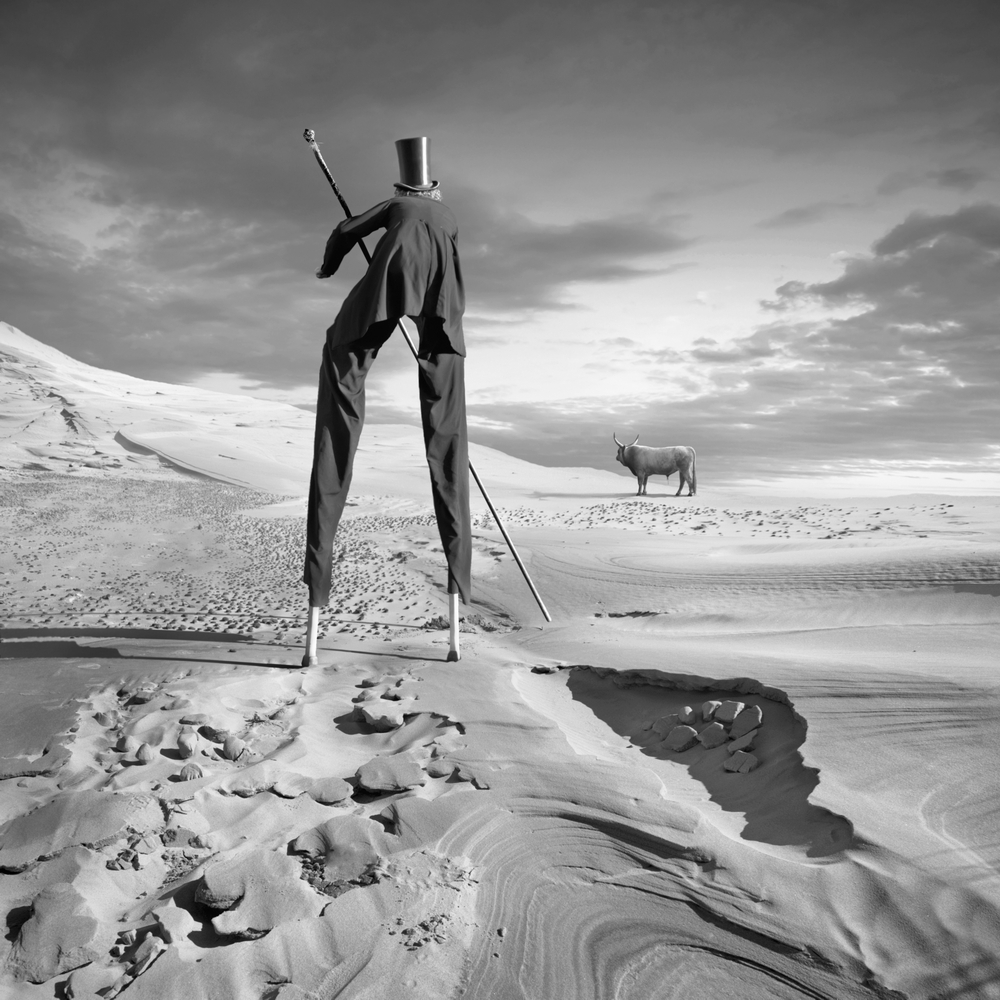 White figure alone in a wide sandy landscape