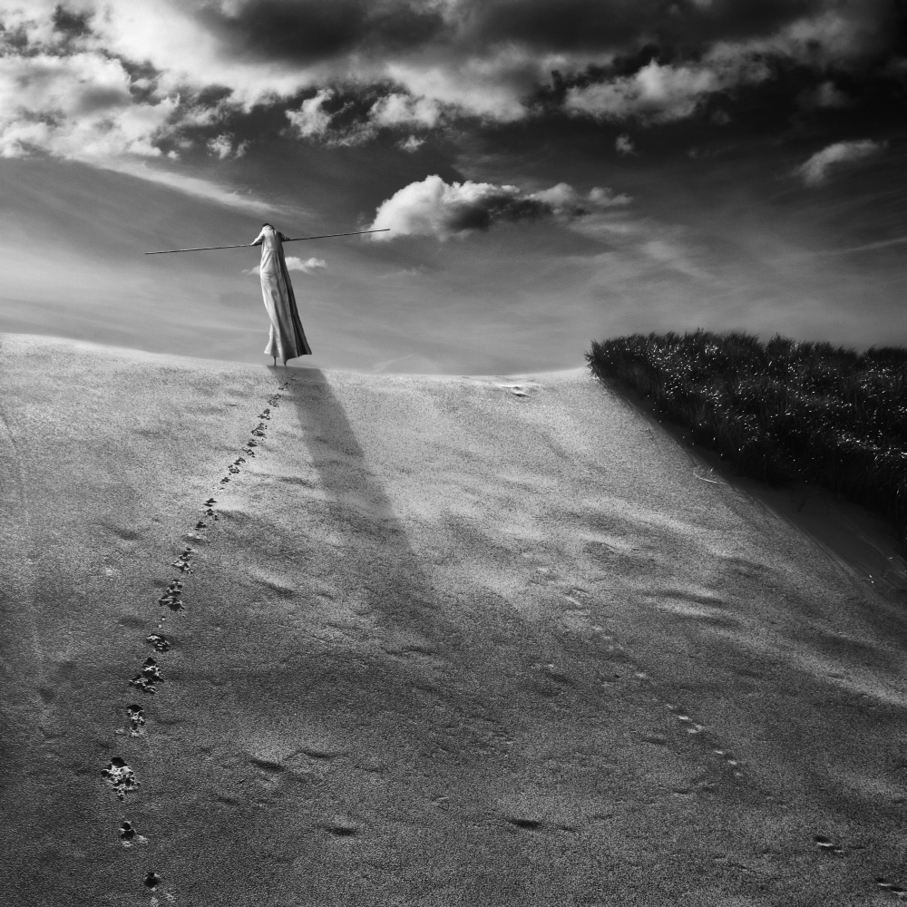White figure floating above a windswept coast