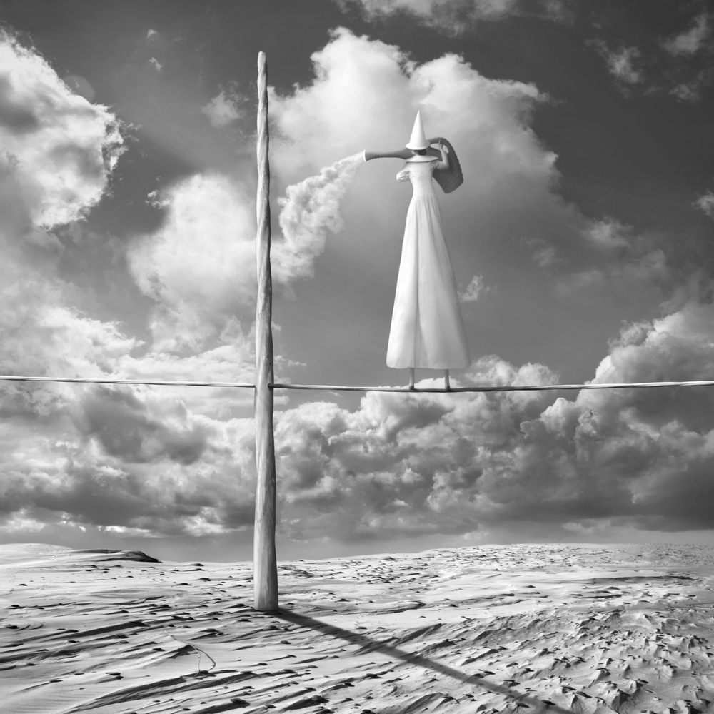 White-clad figure beside a tall pole in clouds