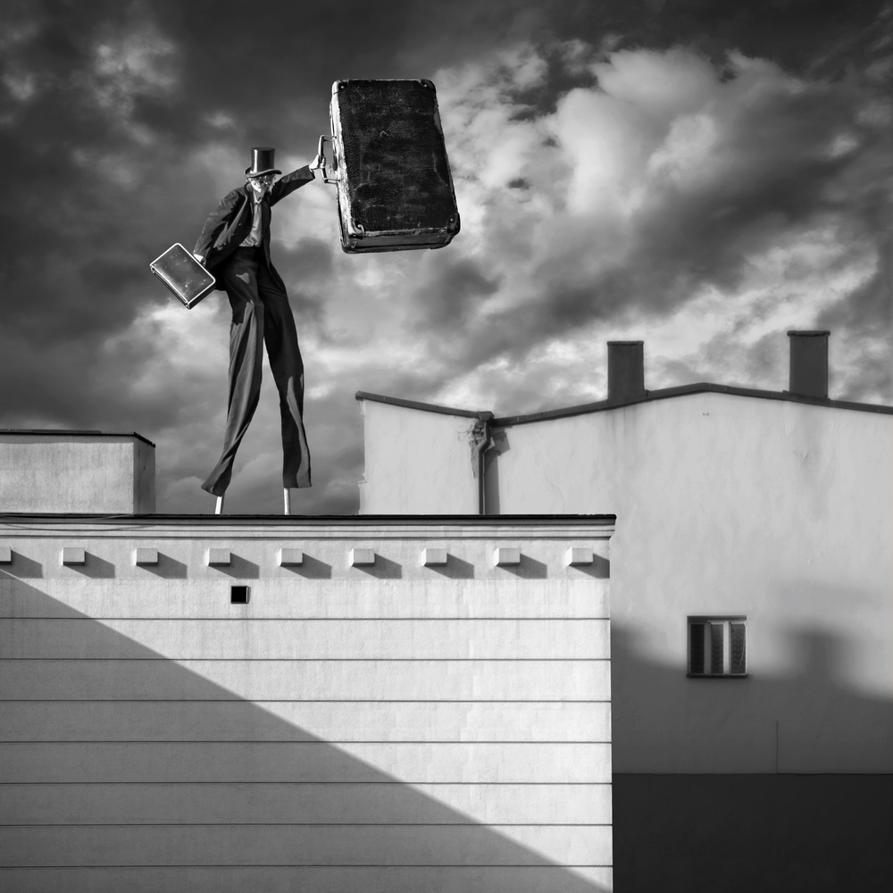 Figure balancing suitcases on a rooftop