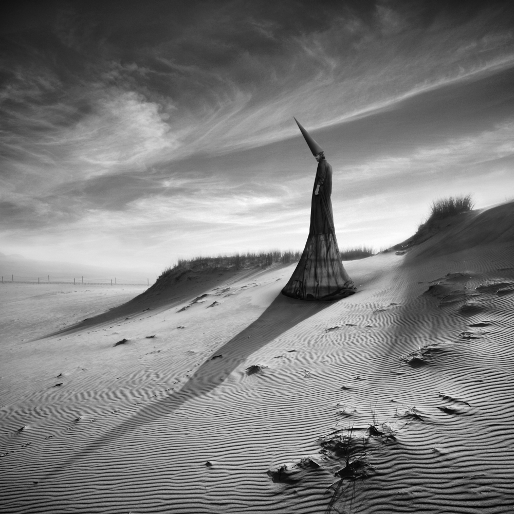 Two white figures beside dunes and clouds