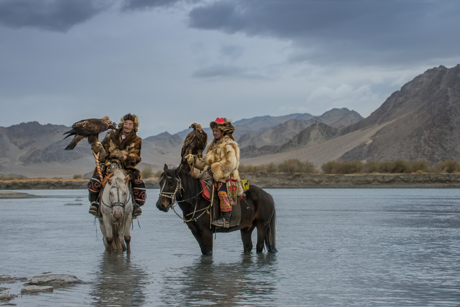 Riders and horses crossing shallow water in Mongolia