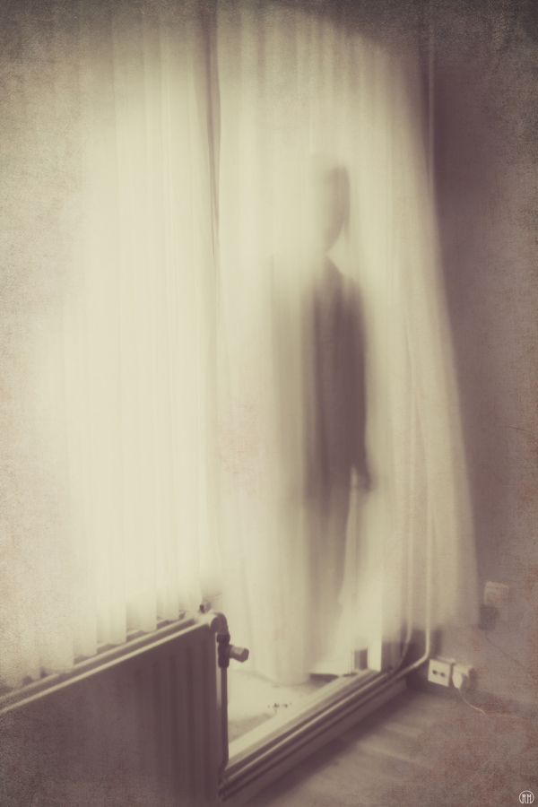 Blurred human-shaped form against curtains