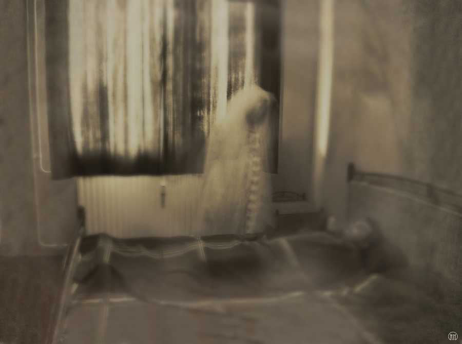 Pale figure standing beside a bed
