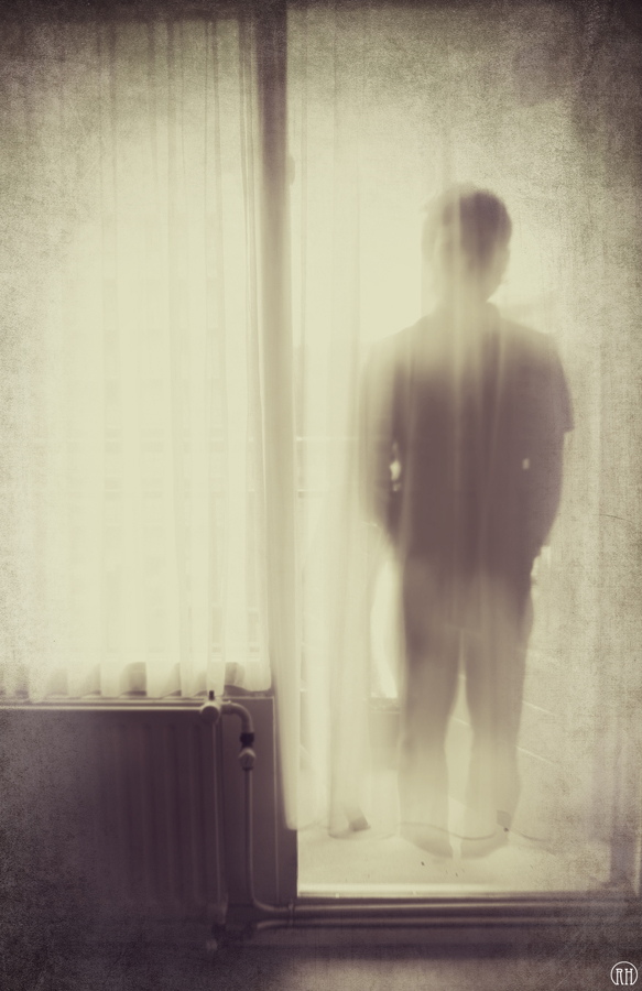 Blurred figure against a pale curtain