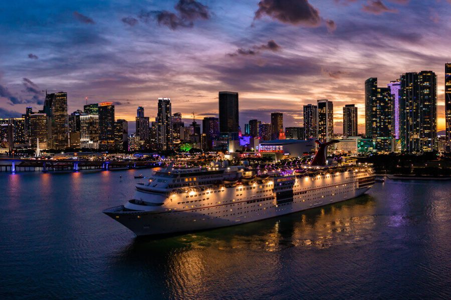 Wide Miami skyline at twilight with a cruise ship in the foreground and illuminated waterfront buildings
