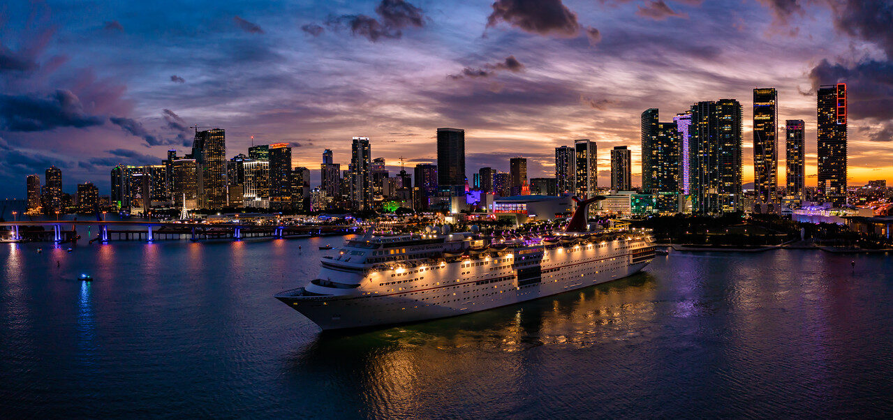 Wide Miami skyline at twilight with a cruise ship in the foreground and illuminated waterfront buildings