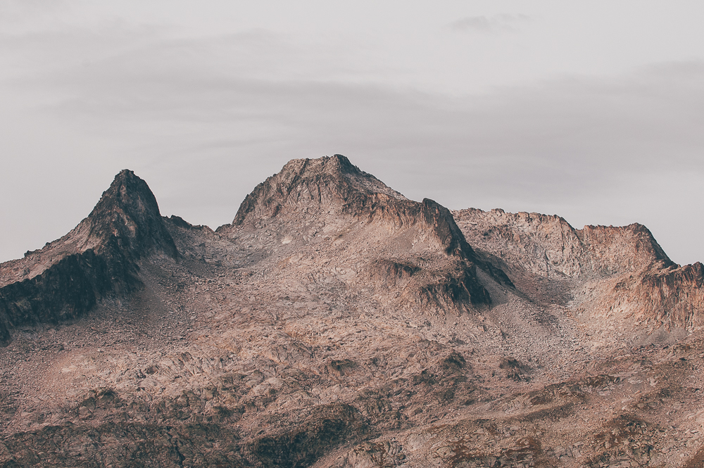 Pale rocky mountain peaks beneath a muted overcast sky