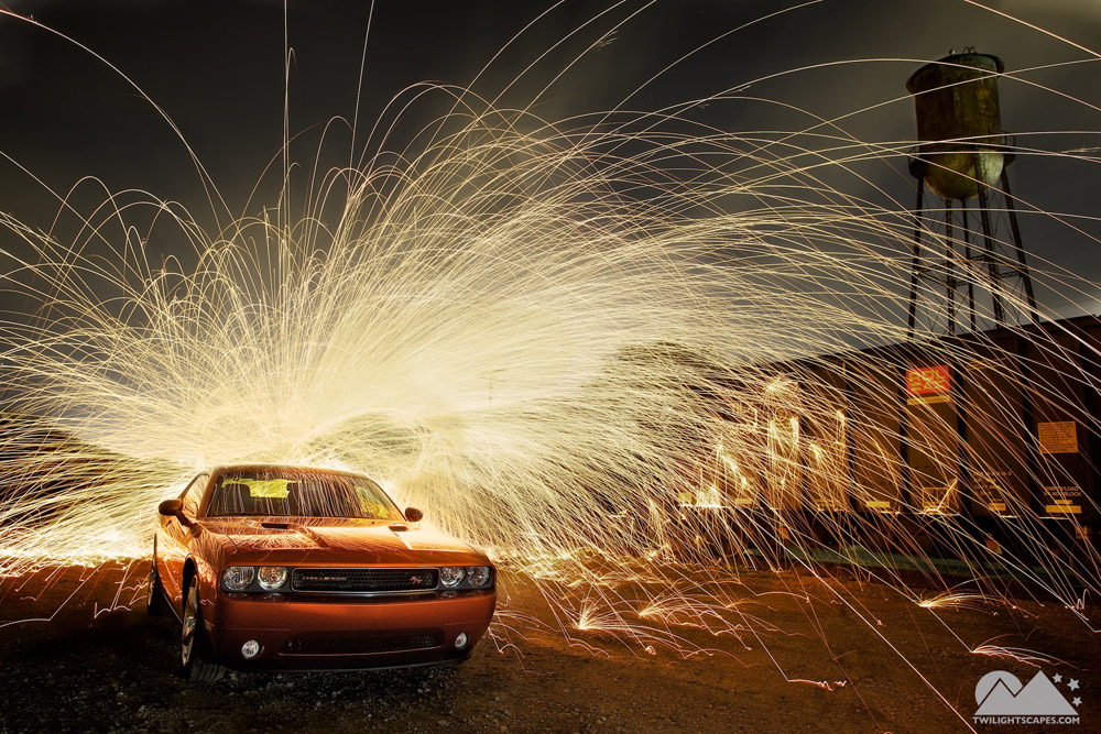 Orange car surrounded by bright radiating light traces in a dark setting