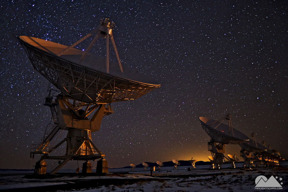 Large radio dishes angled upward beneath a dark star-filled sky