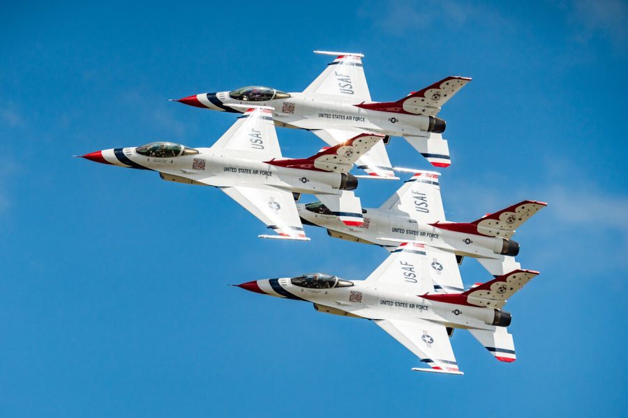 Four U.S. Air Force Thunderbirds jets flying in close formation against blue sky