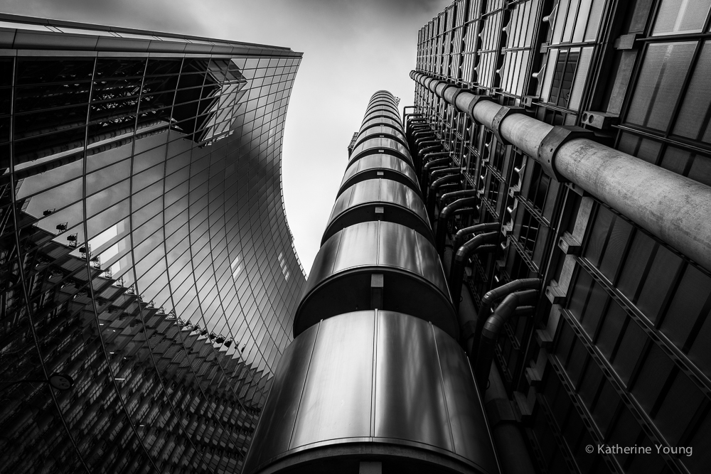 Black and white London building exterior with exposed pipes and a curved glass facade