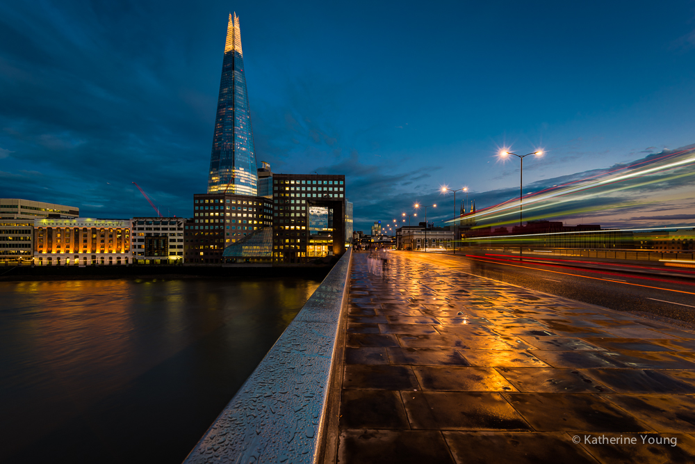 London riverfront view of the Shard at dusk with light trails and wet pavement