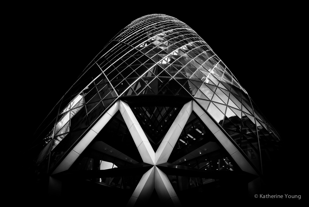Black and white London curved glass tower seen from below with bright diagonal supports