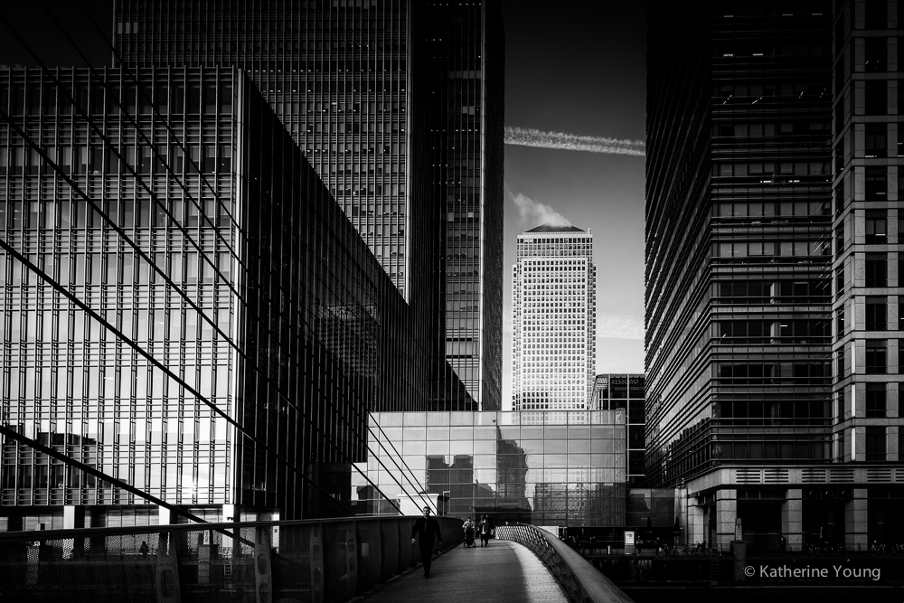 Black and white London street framed by glass office buildings and a distant tower