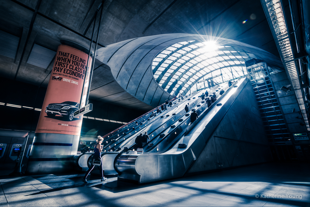 London station escalators in color with daylight crossing a curved glass roof