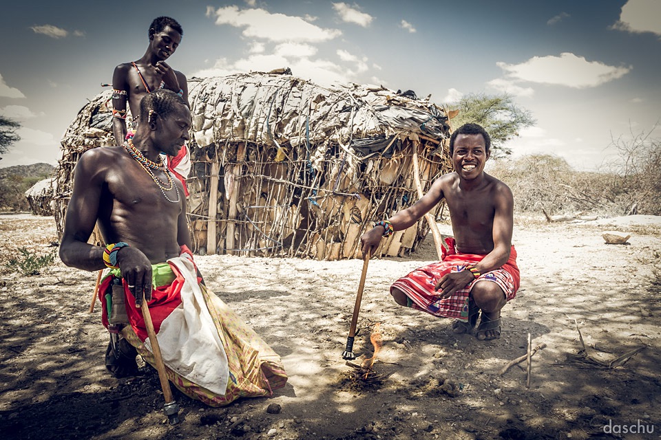 Two Samburu men seated by a thatched hut - Daniel Schuhmacher