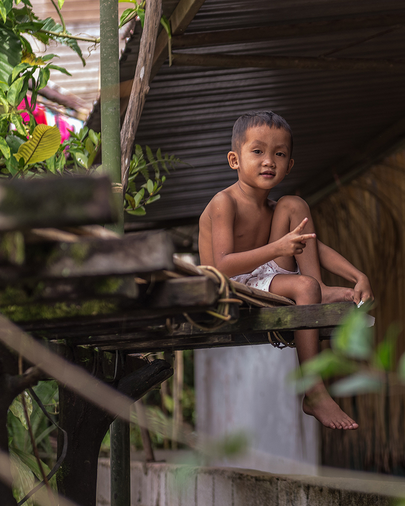 Boy sitting on a longhouse veranda - The Native of Sarawak by Edanan Taiban