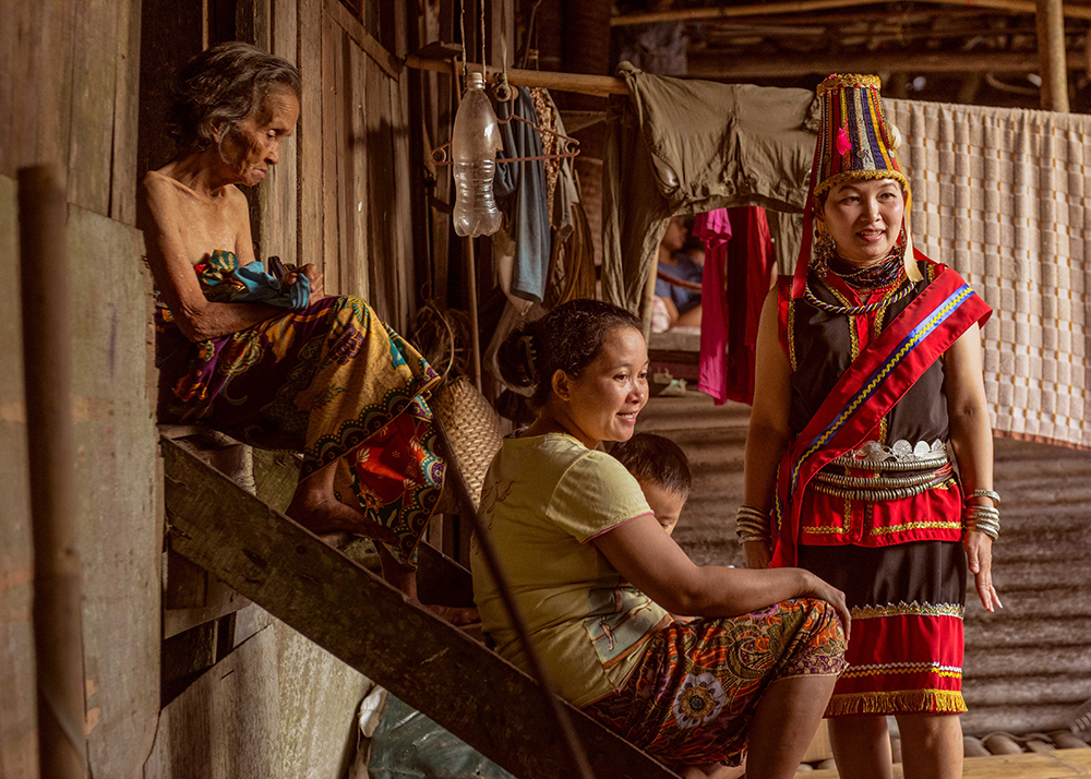 Bidayuh women in traditional dress on longhouse stairs - The Native of Sarawak by Edanan Taiban