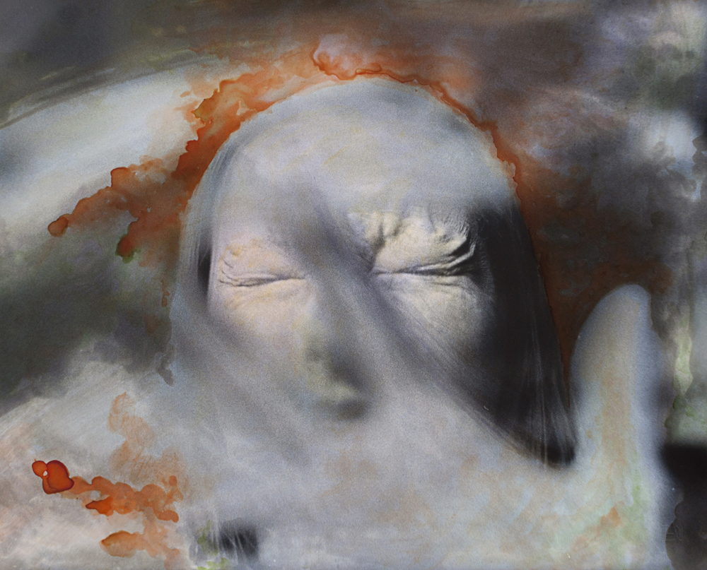 Closed eyes and pale face with a blurred hand and warm orange marks around the head