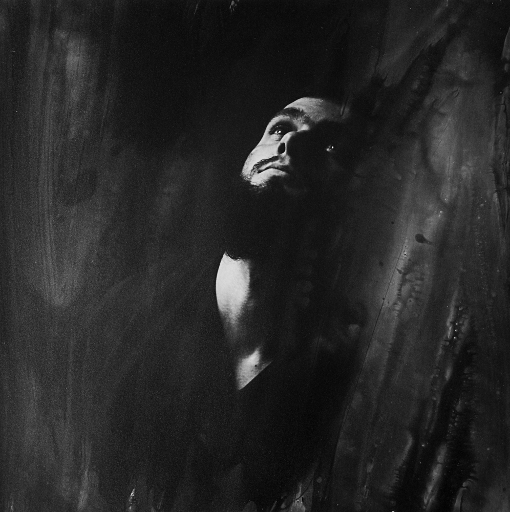 Upturned head and upper torso lit against a dark textured background