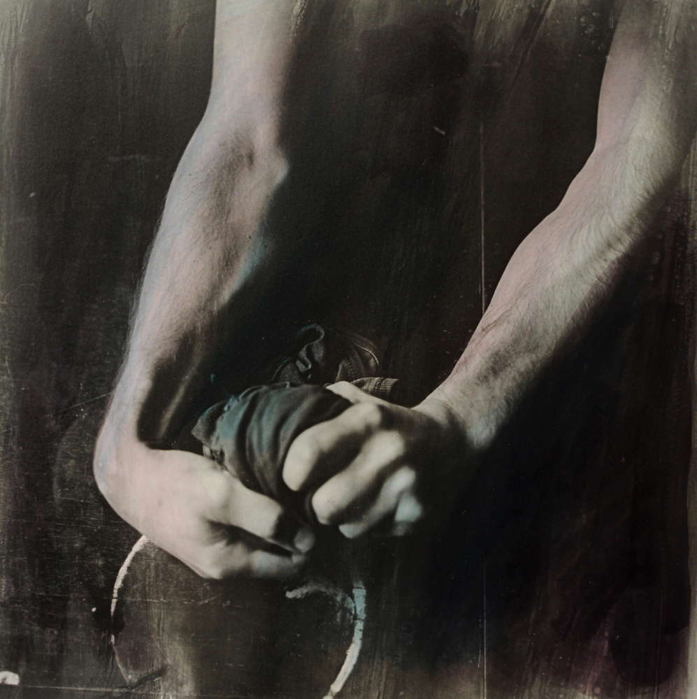 Forearms and clasped hands with a rope-like element in a dark black-and-white image