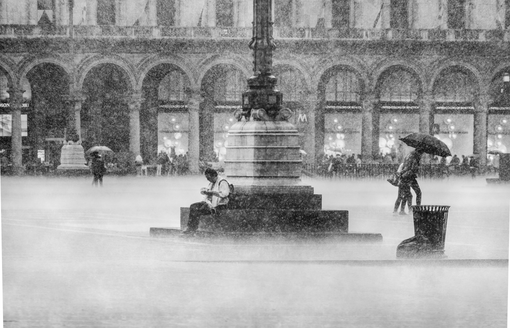 People with umbrellas crossing a Milan piazza in heavy rain - Rain by Marco Gaia