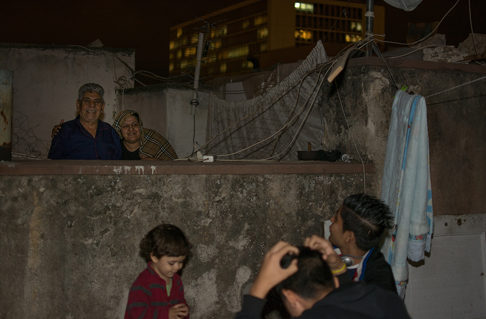 Refugee family on a rooftop at night, Athens - The Unblinking Eyes by Nensi Bogdani