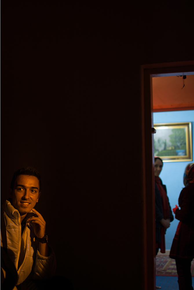 Man smiling in a dark doorway - The Unblinking Eyes by Nensi Bogdani