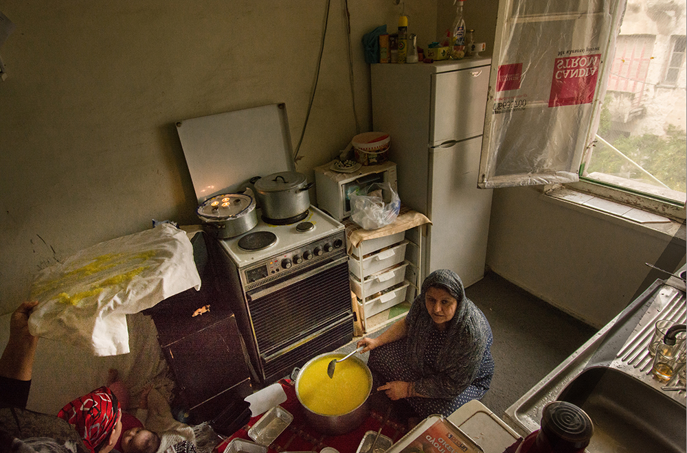 Woman cooking in a small kitchen, Athens - The Unblinking Eyes by Nensi Bogdani