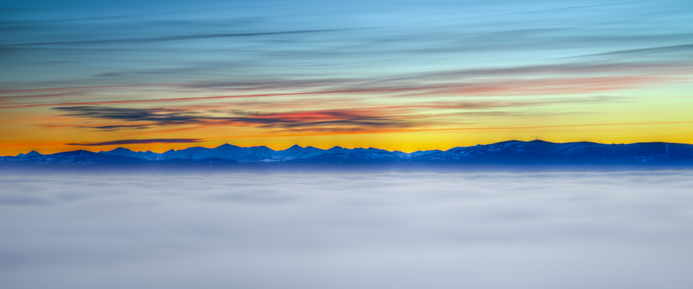 Sea of fog under a sunset sky with distant blue mountains, cloud inversion landscape photo