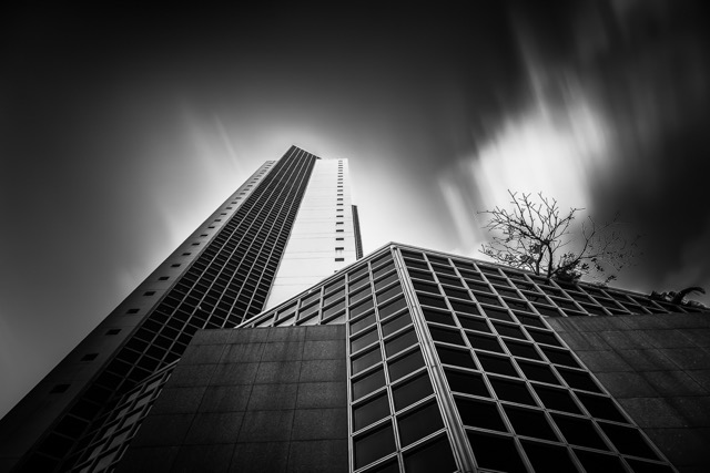 Skyscraper with a rooftop tree against moving clouds, black and white - Contemporary Architecture in Singapore by Ravi Jambunathan