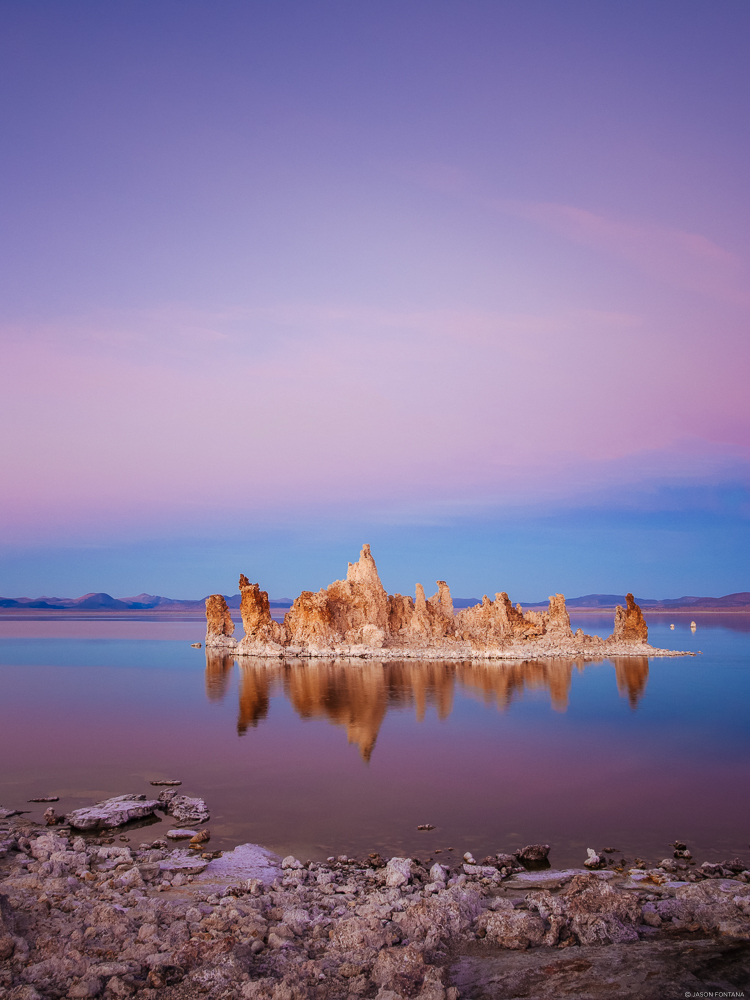 Mineral formations reflected in still water beneath a pink and lavender sky