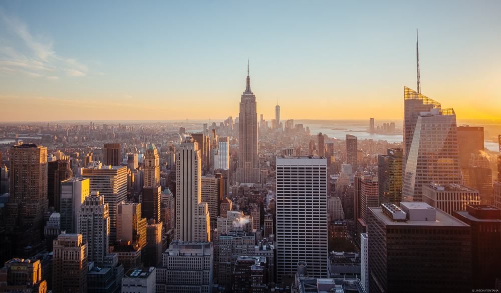 Dense city skyline with a tall central spire under warm evening light