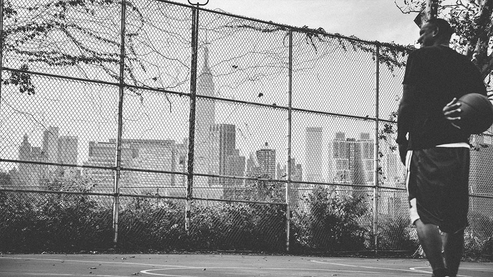 Basketball player by a chain-link fence with the skyline - New Yorkers by Lebrvn Creations