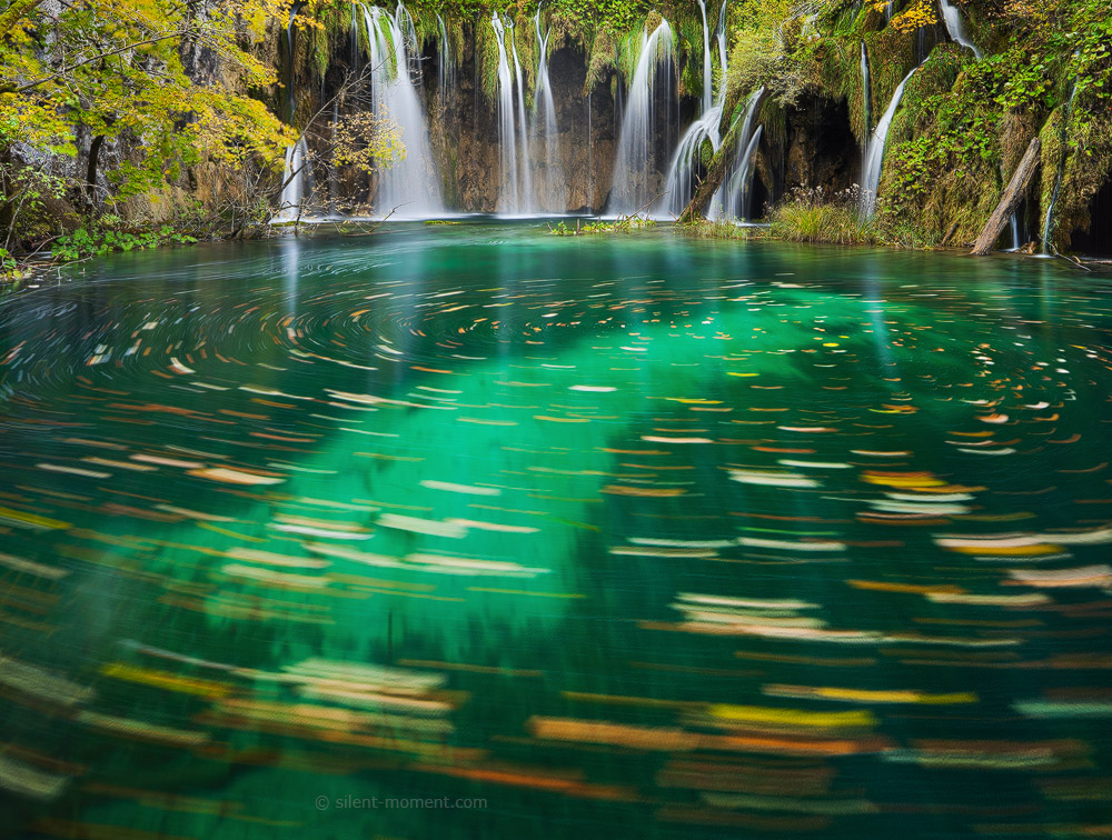Waterfalls descending through green vegetation into turquoise water in Plitvice Lakes National Park, Croatia