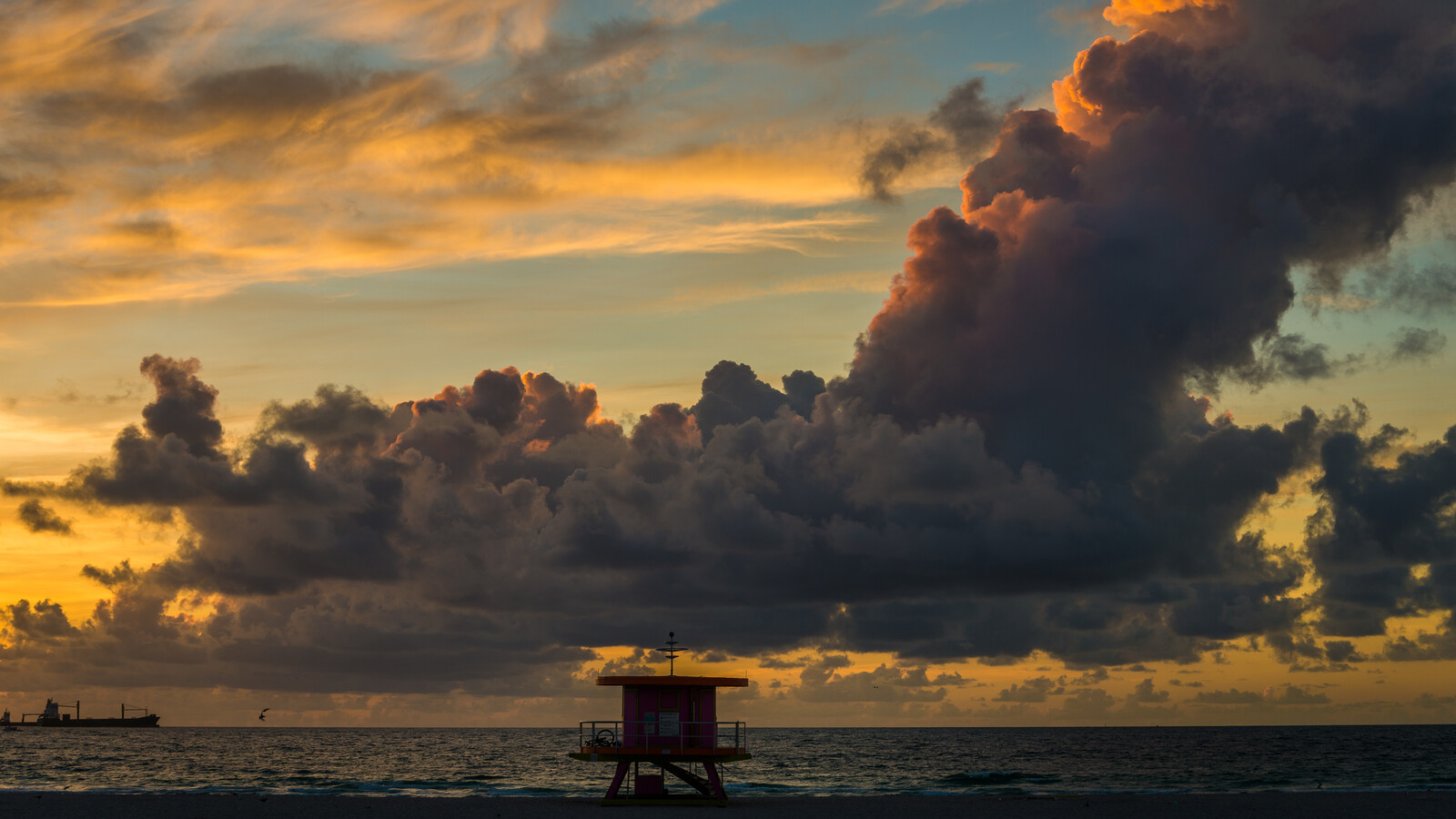 Sunrise storm clouds over a Miami Beach lifeguard tower and the sea