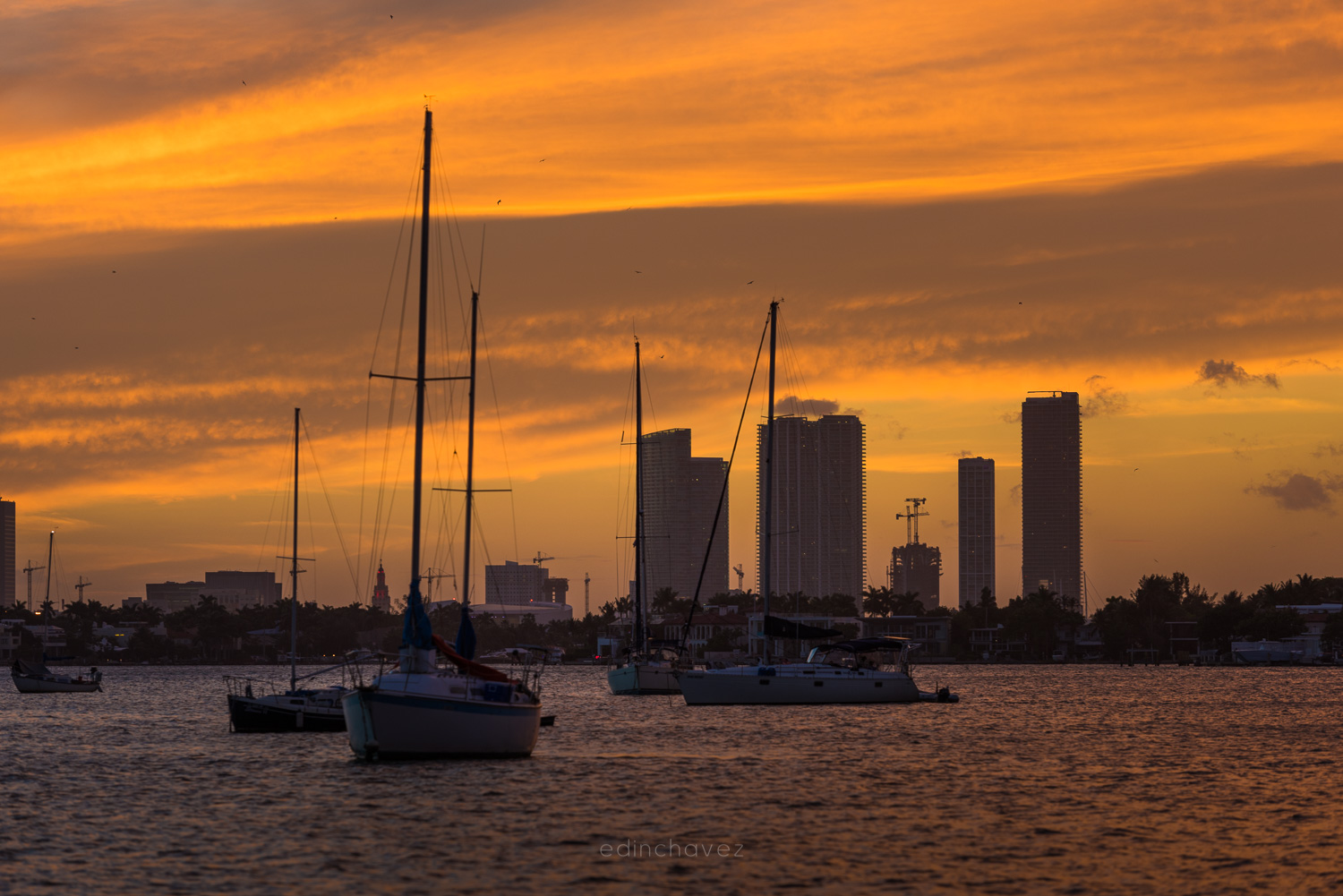 Miami skyline at sunset with sailboats anchored off Miami Beach