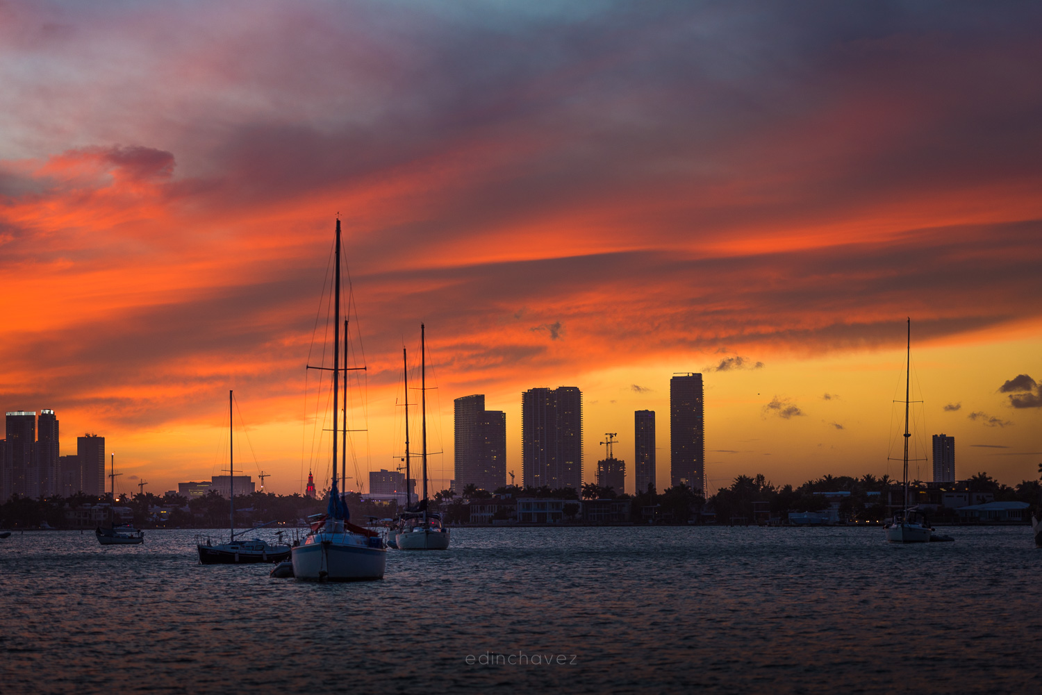 Orange sunset clouds over the Miami skyline and sailboats, Miami Beach