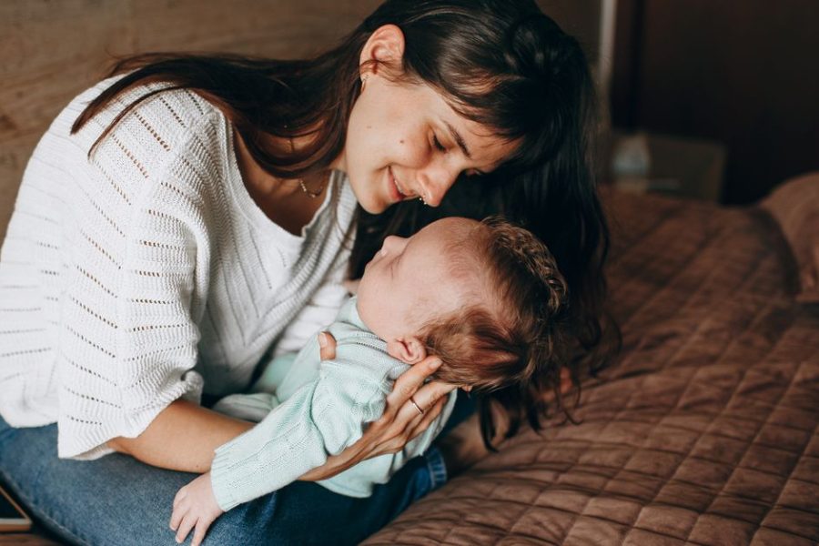Seated mother looking down at her baby held in her arms indoors
