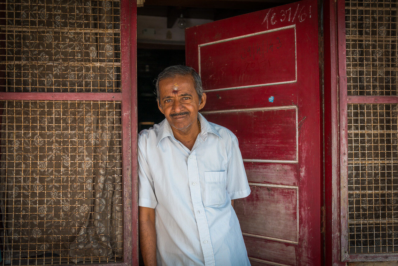 Man in a white shirt beside a red doorway