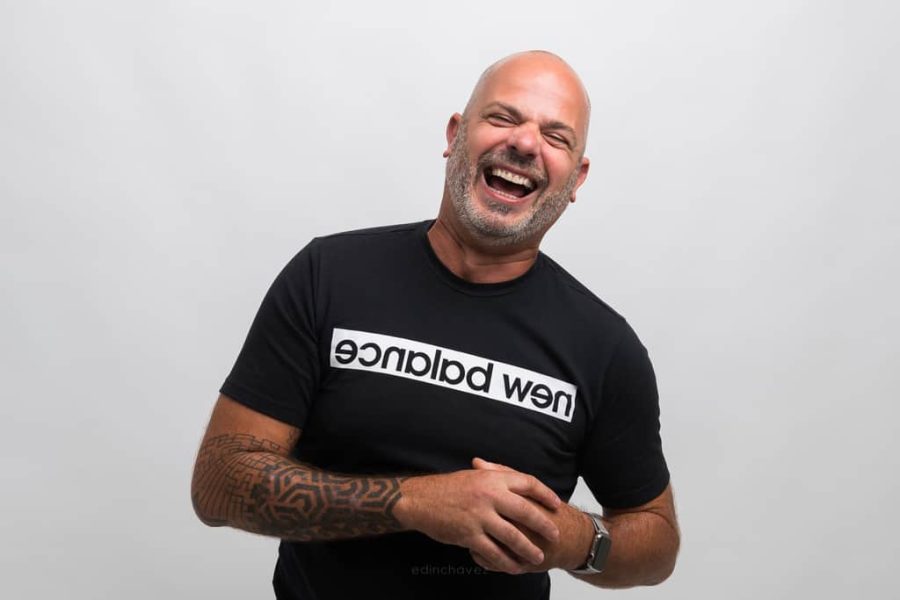 Jorge laughing in a black shirt against a pale studio background