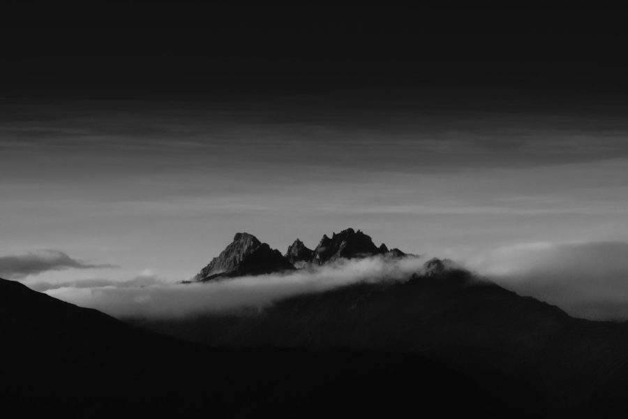Grayscale photograph of the jagged Minaret Peaks breaking through a layer of clouds, New Zealand